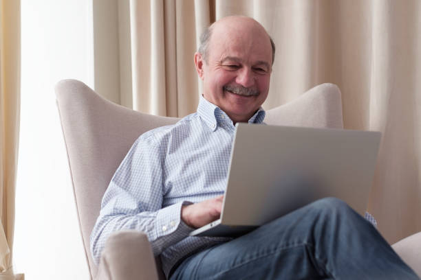 istock Senior man in sofa with laptop computer 1319293303