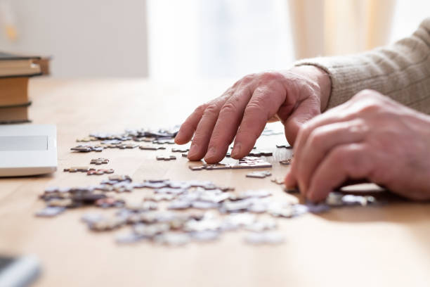 istock Senior male hands working on a puzzle at home 1319293315