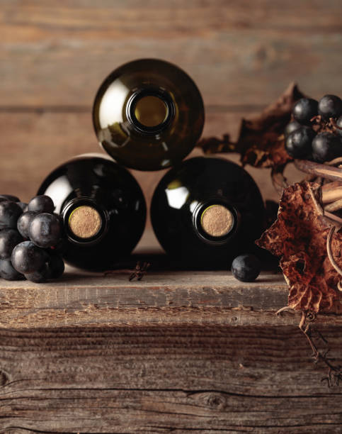 garrafas de vinho tinto com uvas e videira seca em uma velha mesa de madeira. - port wine madeira wine bottle vine - fotografias e filmes do acervo