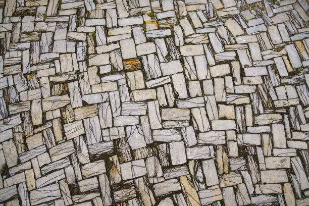 Grey paving slabs made of natural stone laid with a herringbone pattern. View from above. Close up.