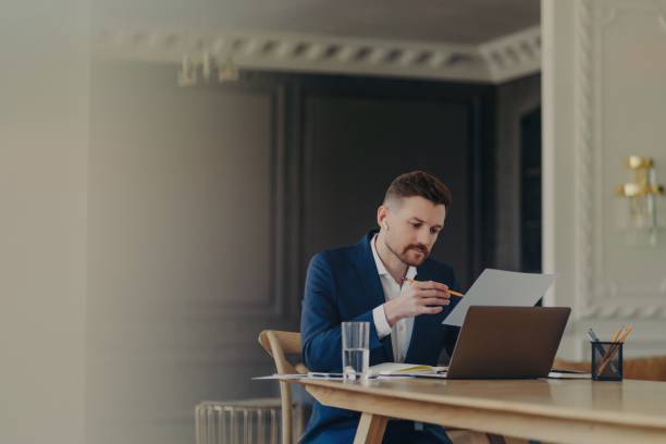 istock Thinking business executive sitting at his desk in front of laptop and analyzing documents 1319296606