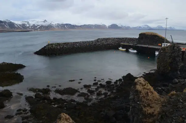 Black lava rock coast with mountains and rock in Hellnar Iceland.