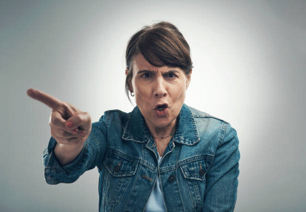 studio portrait of a senior woman yelling against a grey background - behavior women anger pointing imagens e fotografias de stock