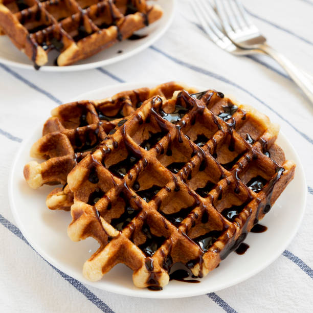 istock Yummy Homemade Belgian Sugar Waffles on a white plate on cloth, low angle view. 1319302565