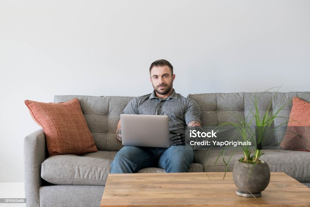 Handicapped man with laptop Man with prosthetic arm using technology Amputee Stock Photo