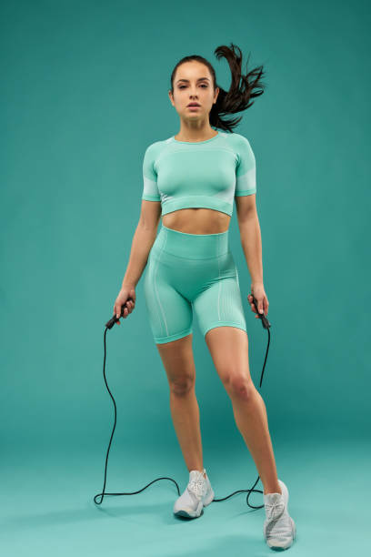 istock Attractive young woman in sportswear using skipping rope 1319303968