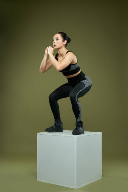 istock Sporty young woman standing on cube and doing squats 1319305522