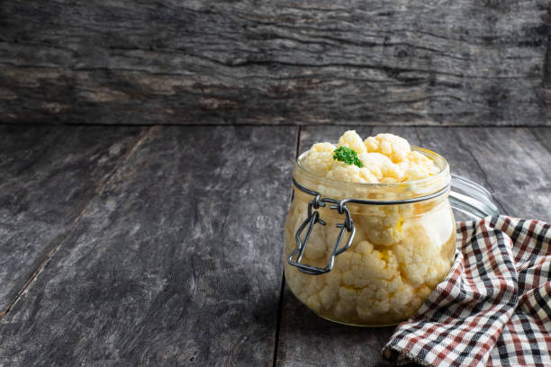 istock Pickled cauliflower in glass jar on rustic wooden table 1319305712