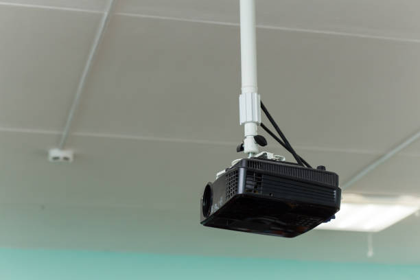 the black video projector is suspended from a long bracket under the ceiling. - conference room sign imagens e fotografias de stock