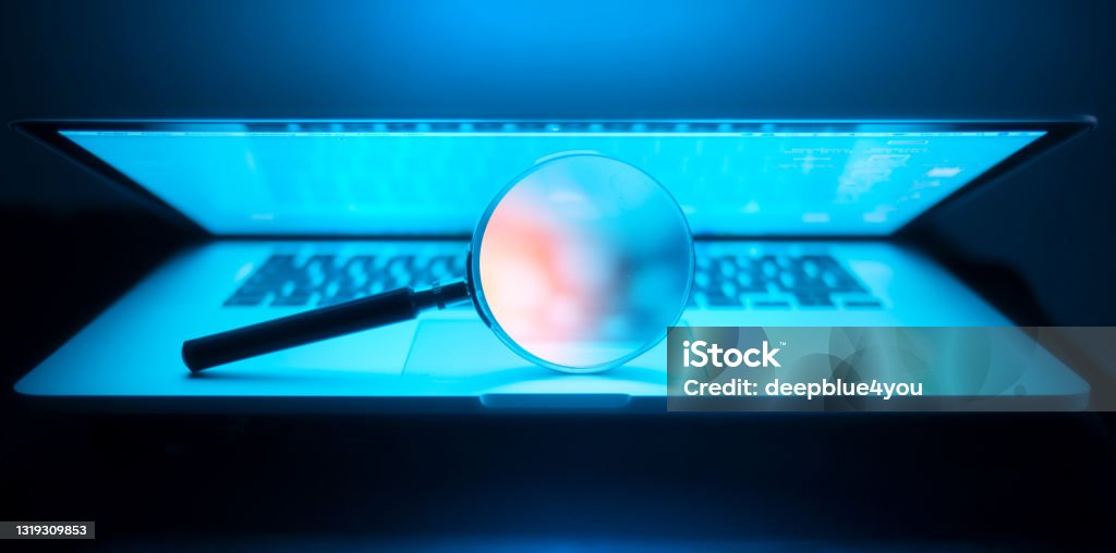 Magnifying glass in the laptop in the dark Laptop keyboard with magnifier searching concept in dark Search Engine Stock Photo