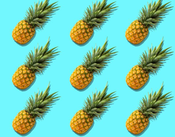 istock Fruit pattern with fresh organic pineapples with hard shadows on bright azure background 1319311041