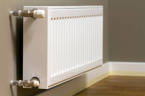 istock White metal heating radiator mounted on gray wall inside a room. 1319312741