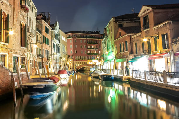 istock Night view of illuminated old architecture, floating boats and light reflections in canals water in Venice, Italy. 1319314561