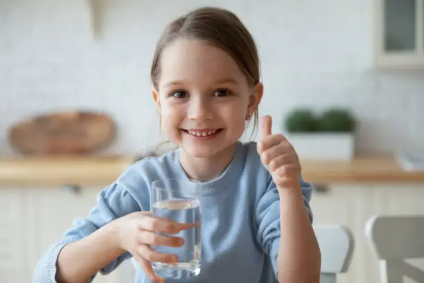 Photo of Portrait of smiling Caucasian girl child drink mineral water