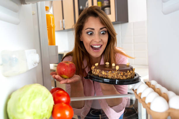 istock Brunette young woman choosing between an apple and a cake 1319316010