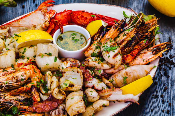 plato de mariscos. langosta a la parrilla, camarones, vieiras, langostinos, pulpo, calamar en plato blanco. - shrimp grilled prepared shrimp barbecue fotografías e imágenes de stock