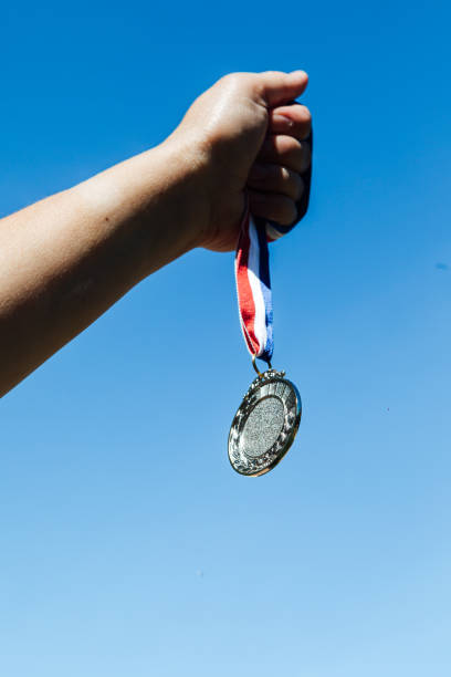 istock A hand holds up a second-place silver medal, with the sky in the background. Victory concept 1319320123