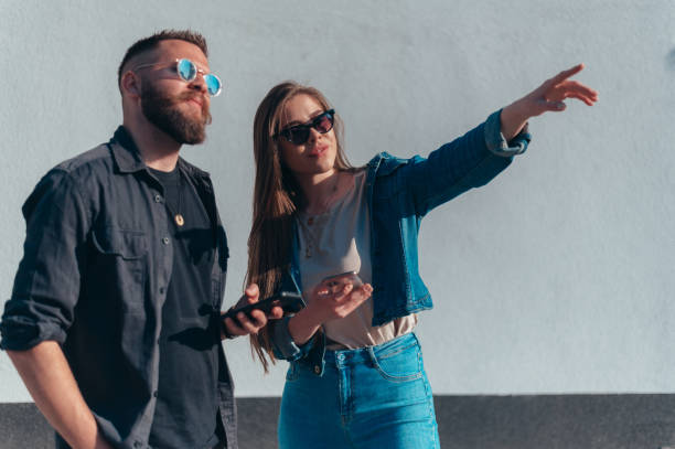 istock Couple using smartphones while standing in front of a white wall 1319321692