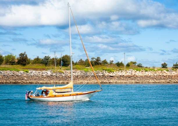 Sandwich, Massachusetts,USA-May 20, 2021-Four friends take advantage of a beautiful May morning to sail along the Cape Cod Canal to get to Cape Cod Bay.  Coast Guard regulations forbid sailboats from using their sails as power while in the Canal.