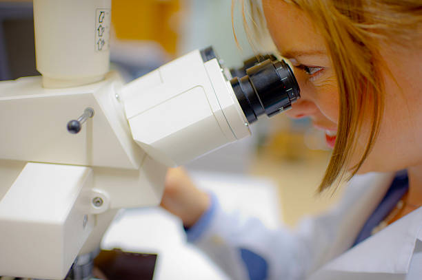 femmina medico con microscopio in un laboratorio - biotechnology student laboratory nurse foto e immagini stock