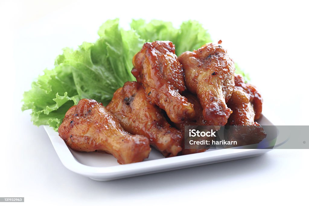 BBQ glazed wings served on a white plate with lettuce Plate of chicken wings on white background Chicken Wing Stock Photo