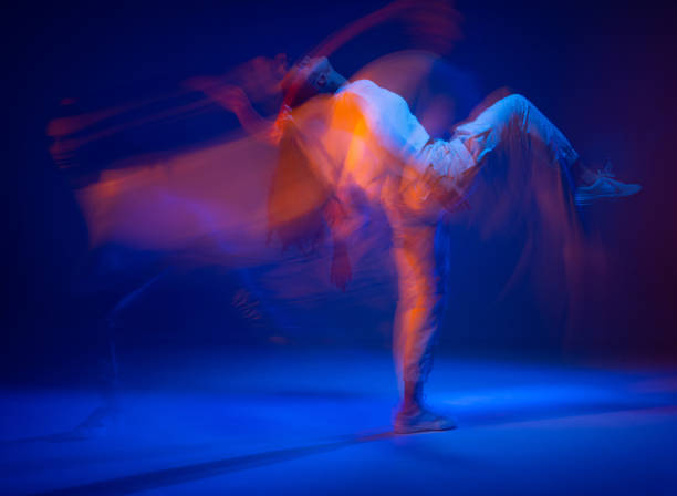 istock Dancing sportive female in colorful neon light. Expressive contemporary dance. Studio photography with long exposure 1319348308