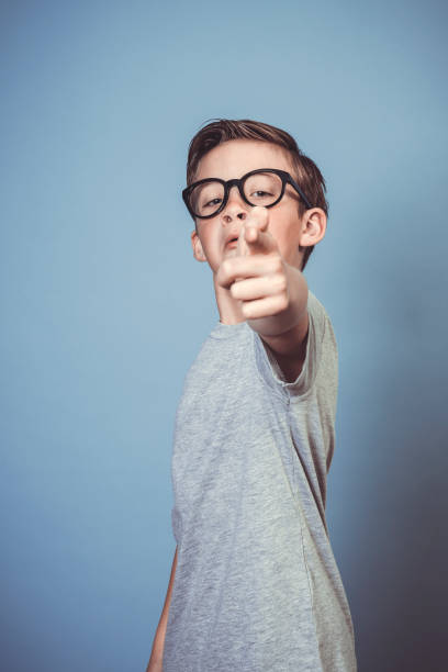 istock cool school boy with thick black glasses posing on blue background 1319355321