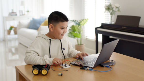 istock Young asia student remotely learn online at home in coding robot car and electronic board cable in STEM, STEAM, mathematics engineering science technology computer code in robotics for kids concept. 1319365022