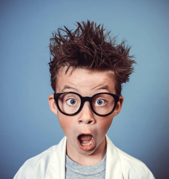 cool school boy with thick black glasses is dressed as mad scientist with white coat
