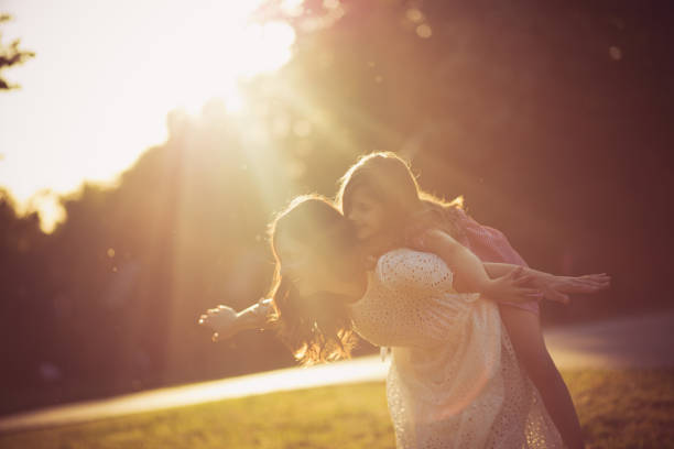 Time for adventure. Mother and daughter playing in nature. Mom carrying kid on piggyback.