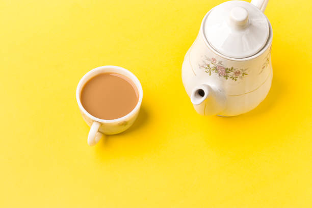 istock Milk tea on white cup with white kettle on yellow background stock image. 1319386721