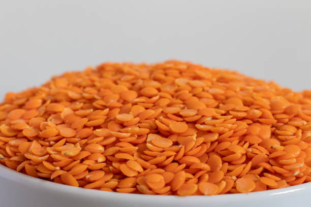 Various types of lentils and legumes are displayed in glass jars, showcasing their vibrant colors against a contrasting black background, creating a visually appealing arrangement - food and drink, healthy eating