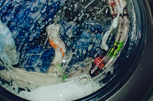 Closeup of washing machine full of dirty clothes. Laundry washing process.