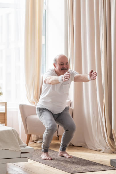 istock Senior man practicing yoga at home doing Chair pose, Utkatasana 1319397606