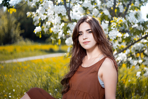 Portrait of a young woman on the background of a flowering apple tree. Shallow focus.