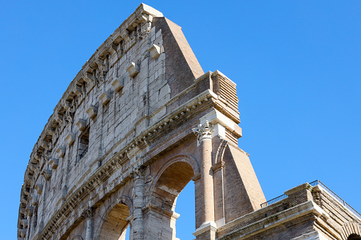 detail of the ancient perimeter walls upper corner of the Colosseum viewed from the outside with blue sky, Rome Italy