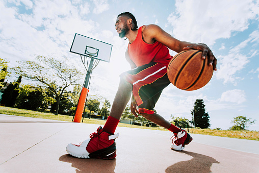 Cinematic College Basketball Tournament: Two Young Successful Diverse Teams Play a Championship Match in a Modern Arena. Excited African Player Scores a Perfect Slam Dunk with Two Hands.