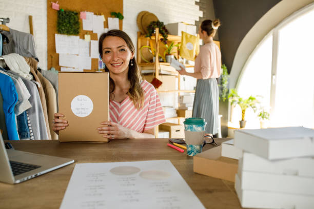 istock Young female entrepreneur holding a package and smiling at camera 1319403250