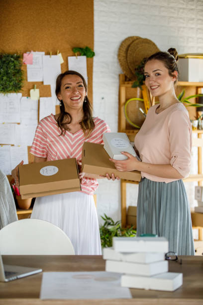 istock Female entrepreneurs smiling at camera while holding packages 1319403265