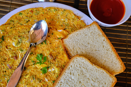 Flat lay of Simple breakfast, Scrambled egg with bread in a white plate on a wooden background.