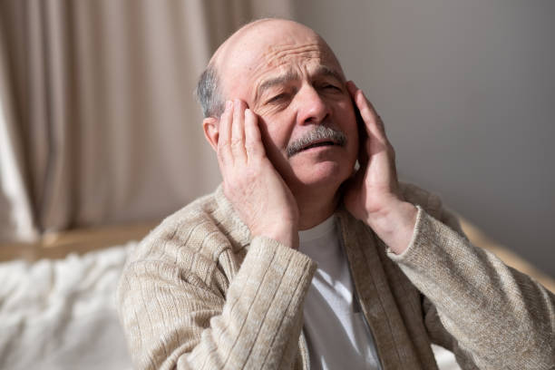 istock Old man feels pain in his temples sitting at home alone. 1319404422