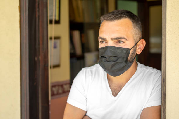 istock Handsome looking from door to quarantine with mask 1319406059