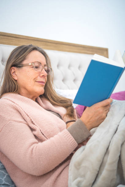 istock Smiling Senior Woman Reading in Bed 1319411106