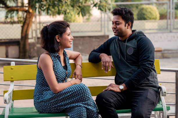 istock Romantic Indian couple sitting on bench and talking to each other 1319413581