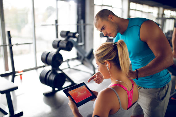 istock Young woman discussing workout progress with fitness instructor 1319415066