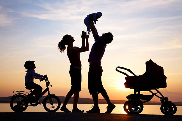 Silhouette of happy family playing at sea coast stock photo