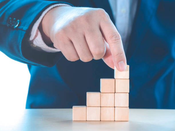 istock Hand of businessman arranging empty wooden cube stacking as step stair on table for input wording and infographic icon. Business concept growth success process. 1319416775