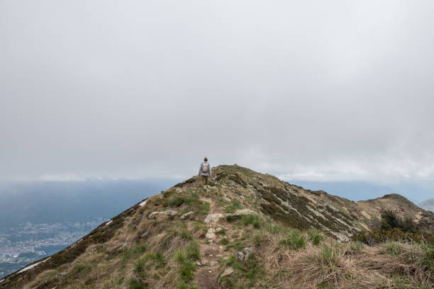 istock Young man hiking on mountain ridge, overcast sky 1319416845