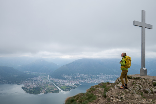 She carries a backpack, mountain range on background.
Ticino Canton, Switzerland