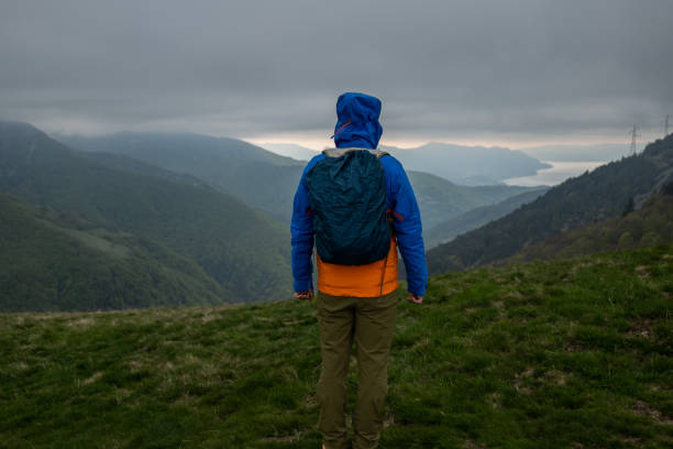 istock Young man hiking on mountain ridge, storm cloud 1319419845